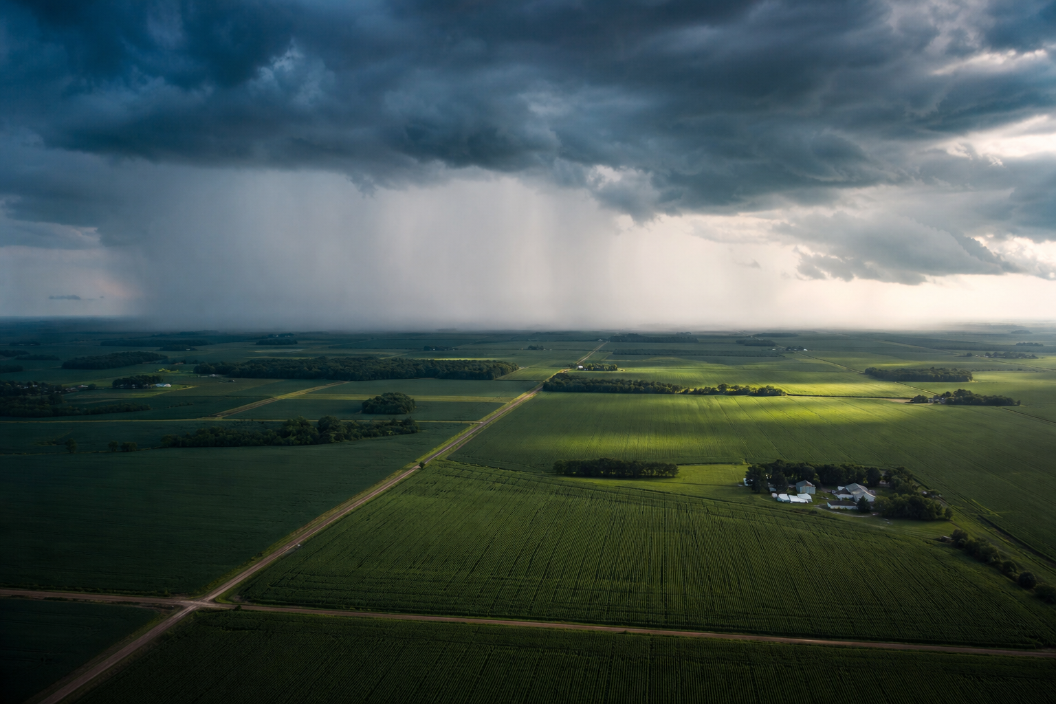 Aerial view of farmland with a rain shower crossing distant fields